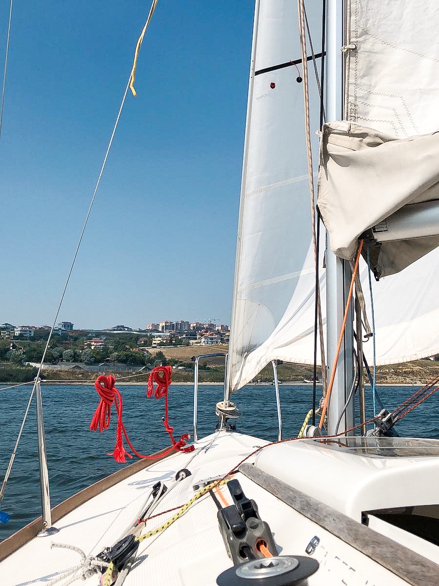 Close-up detail of sailboat parts including boom, mainsheet, and winch showing essential sailing terminology
