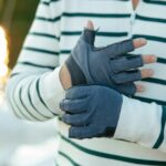 man wearing gloves, standing on boat deck in the evening sunshine.