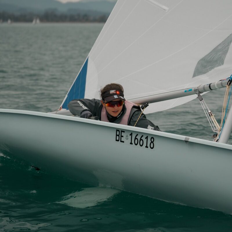 man in blue and black jacket riding on white boat during daytime